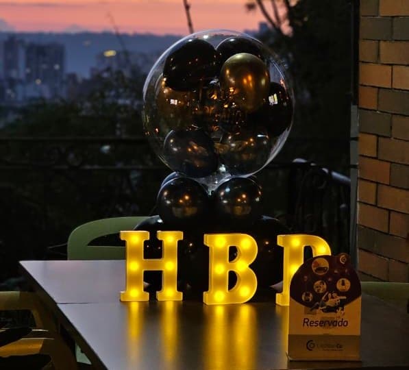 Mesa decorada con globos y letras luminosas HBD en la terraza de Ritmo